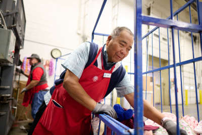 thrift store worker in a red apron helps sort donations